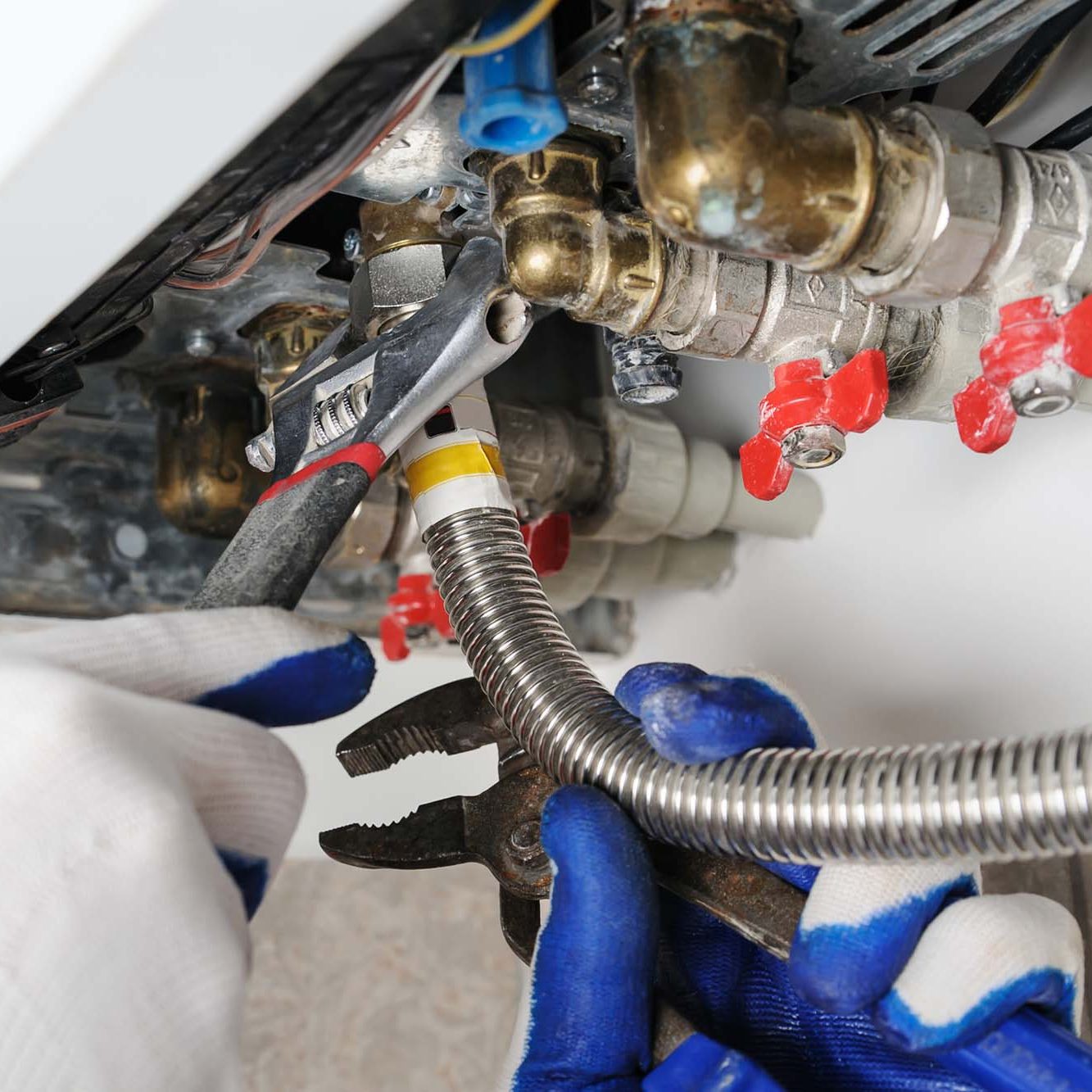 Plumber attaches to pipe gas boiler using adjustable wrench.